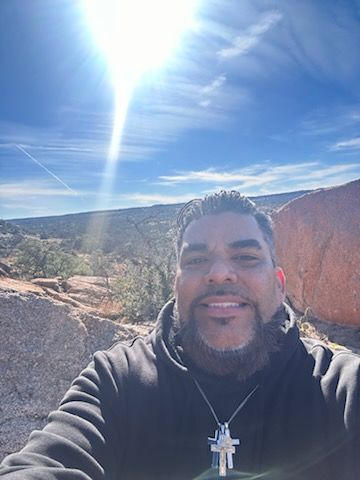 A series of selfie photos taken at the rim of a desert canyon with blue skies and rocky terrain in the background.