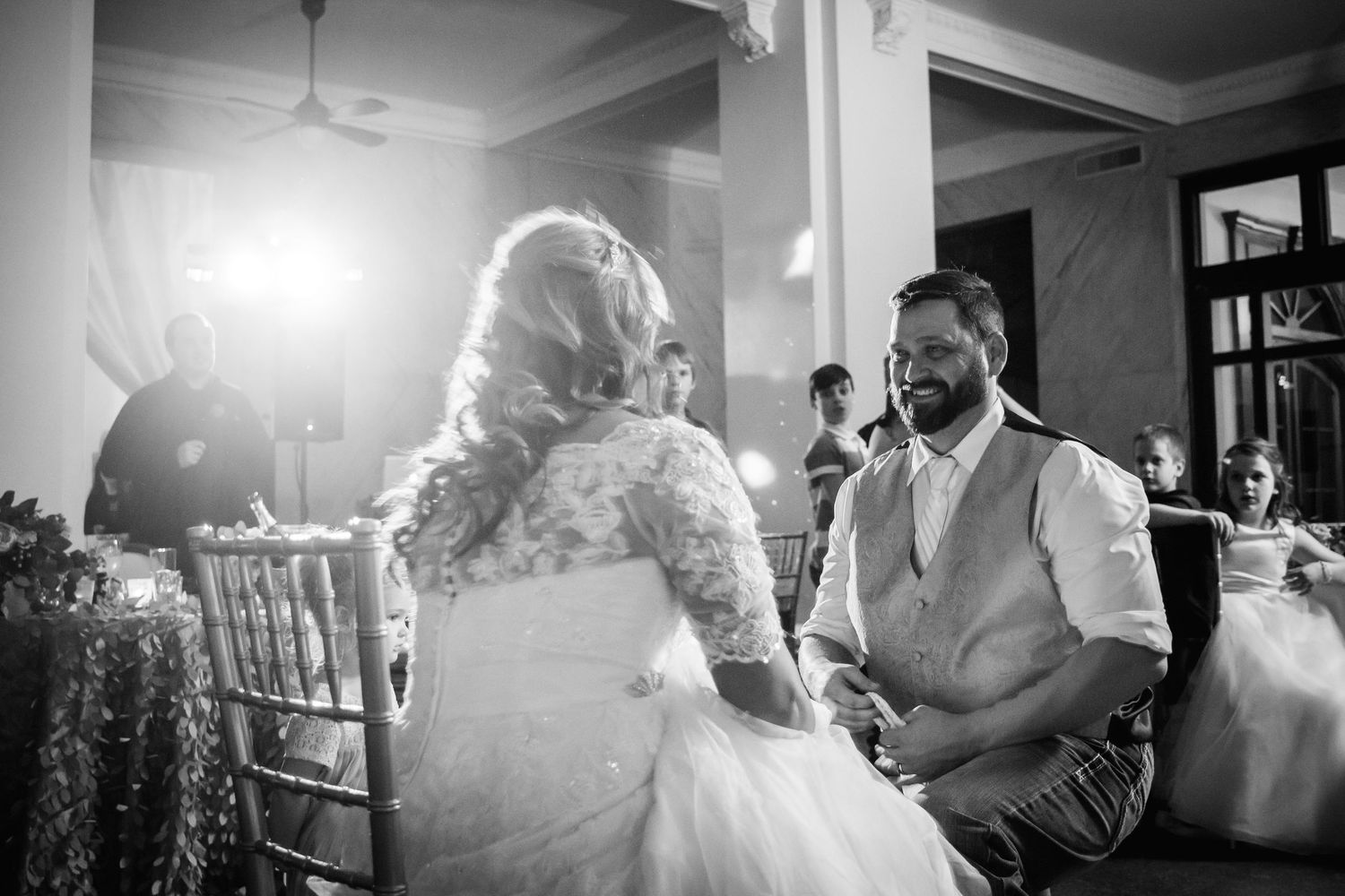 Black and white candid moment at a wedding reception with couple sharing a tender moment at their decorated table.
