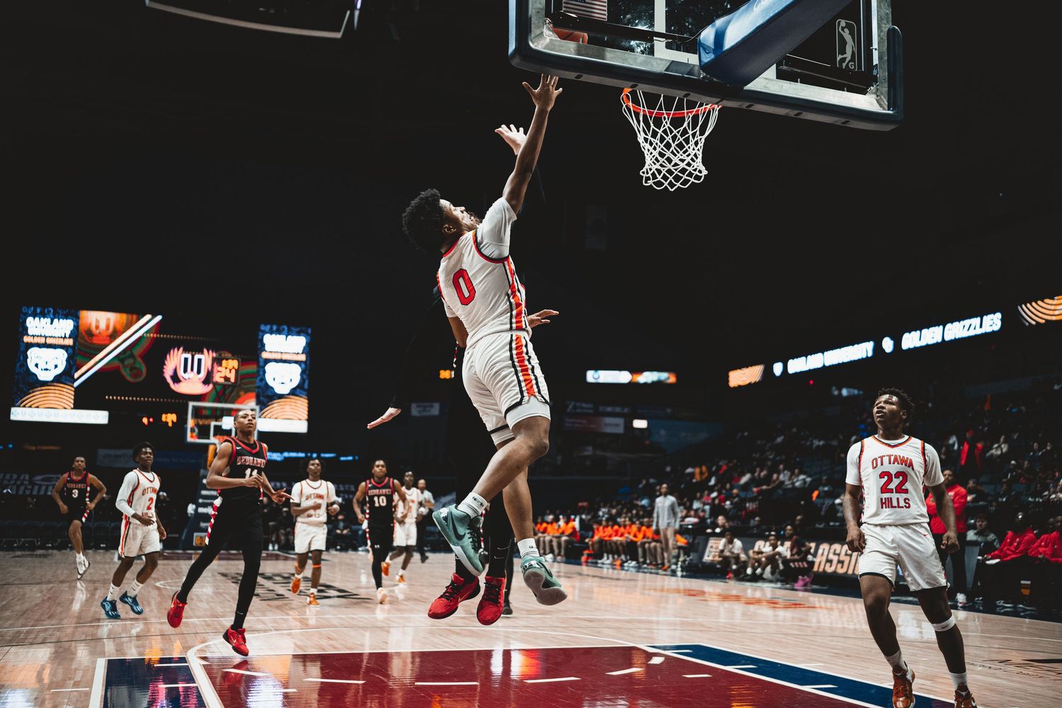 Basketball players in action during professional game with dramatic arena lighting.