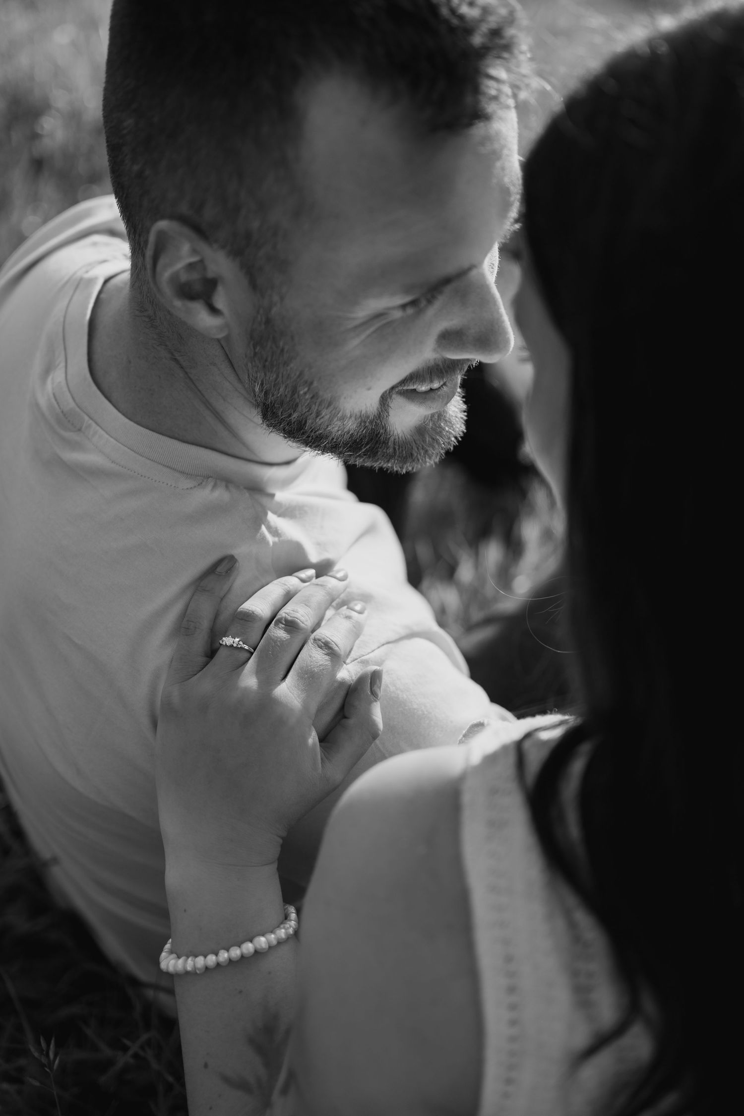 Black and white portrait of a couple sharing an intimate kiss in front of a stone building.