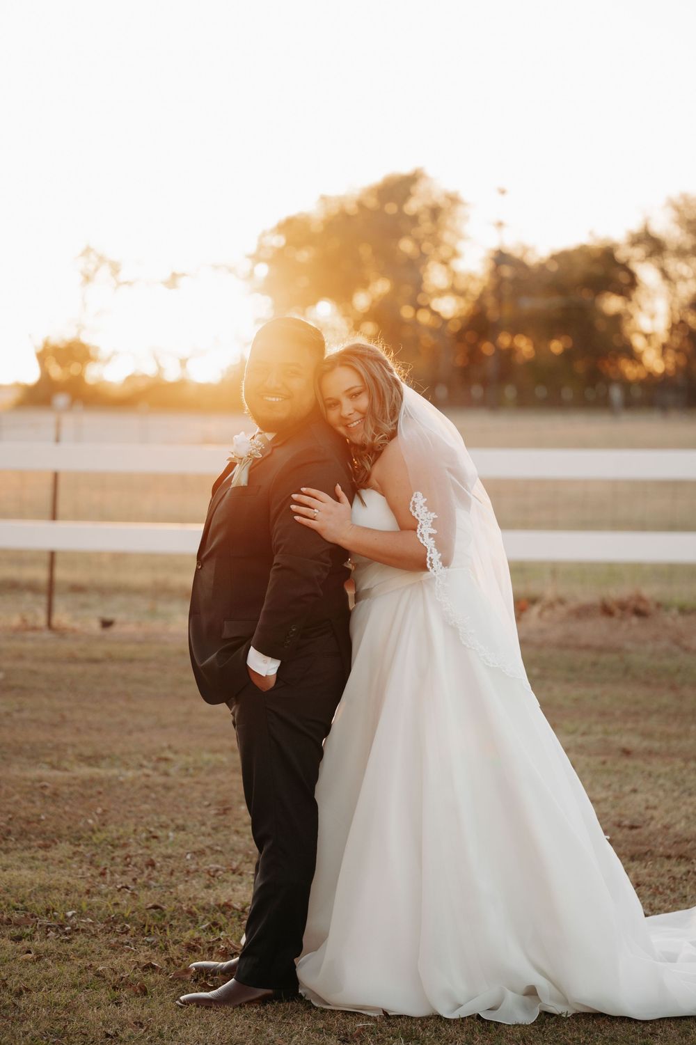 Newlyweds share romantic moments on a grassy field during golden hour.