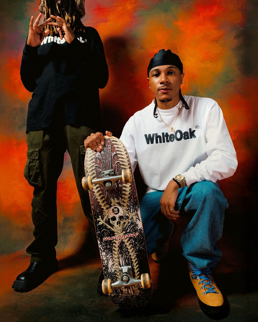 A person wearing a white WhiteOak shirt and jeans sits casually against a dramatic orange and black backdrop.