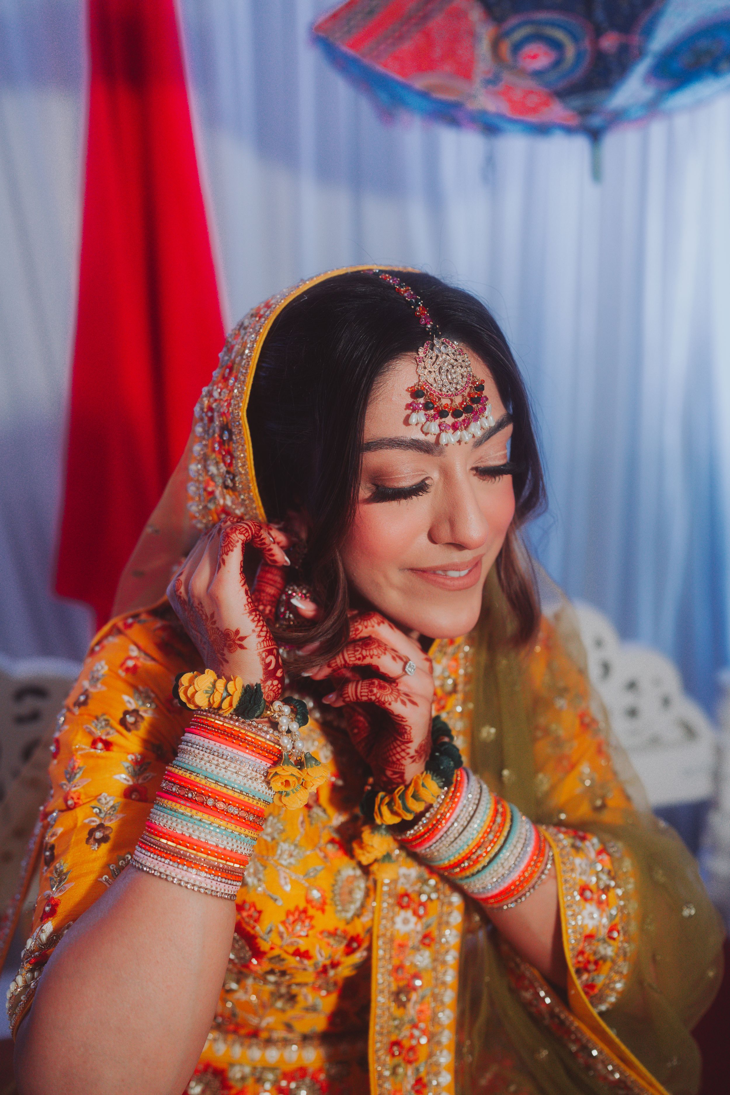 Traditional bridal portrait showing detailed mehndi, jewelry and yellow embroidered outfit.