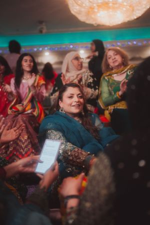 Wedding guests in vibrant cultural attire enjoying festivities under crystal chandelier lighting.