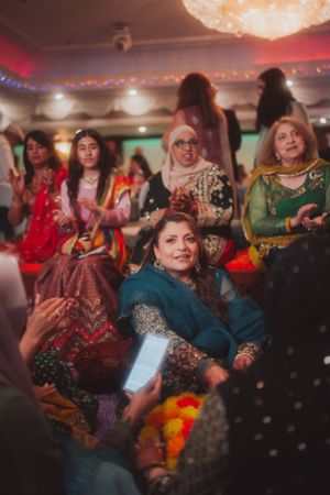 Guests in colorful traditional South Asian attire enjoying a celebratory event indoors.