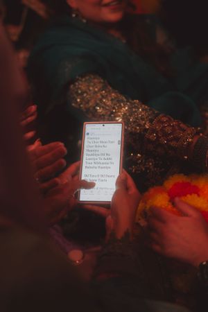 Hand holding phone screen displaying text against dark background with festive decorations.