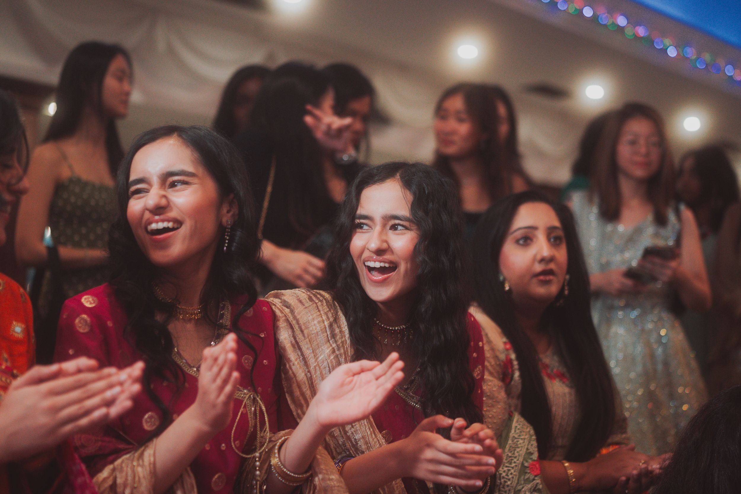 Wedding guests clapping and celebrating during traditional Indian ceremony.