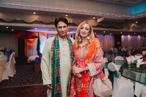 A couple in traditional South Asian wedding attire poses together at an elegant reception venue.