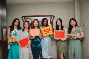 Group poses holding colorful signs at wedding celebration event.