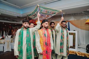 Groomsmen in matching green and white traditional outfits posing together at wedding celebration.