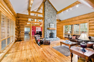 Modern log home interior with stone fireplace, wood floors and vaulted ceilings.