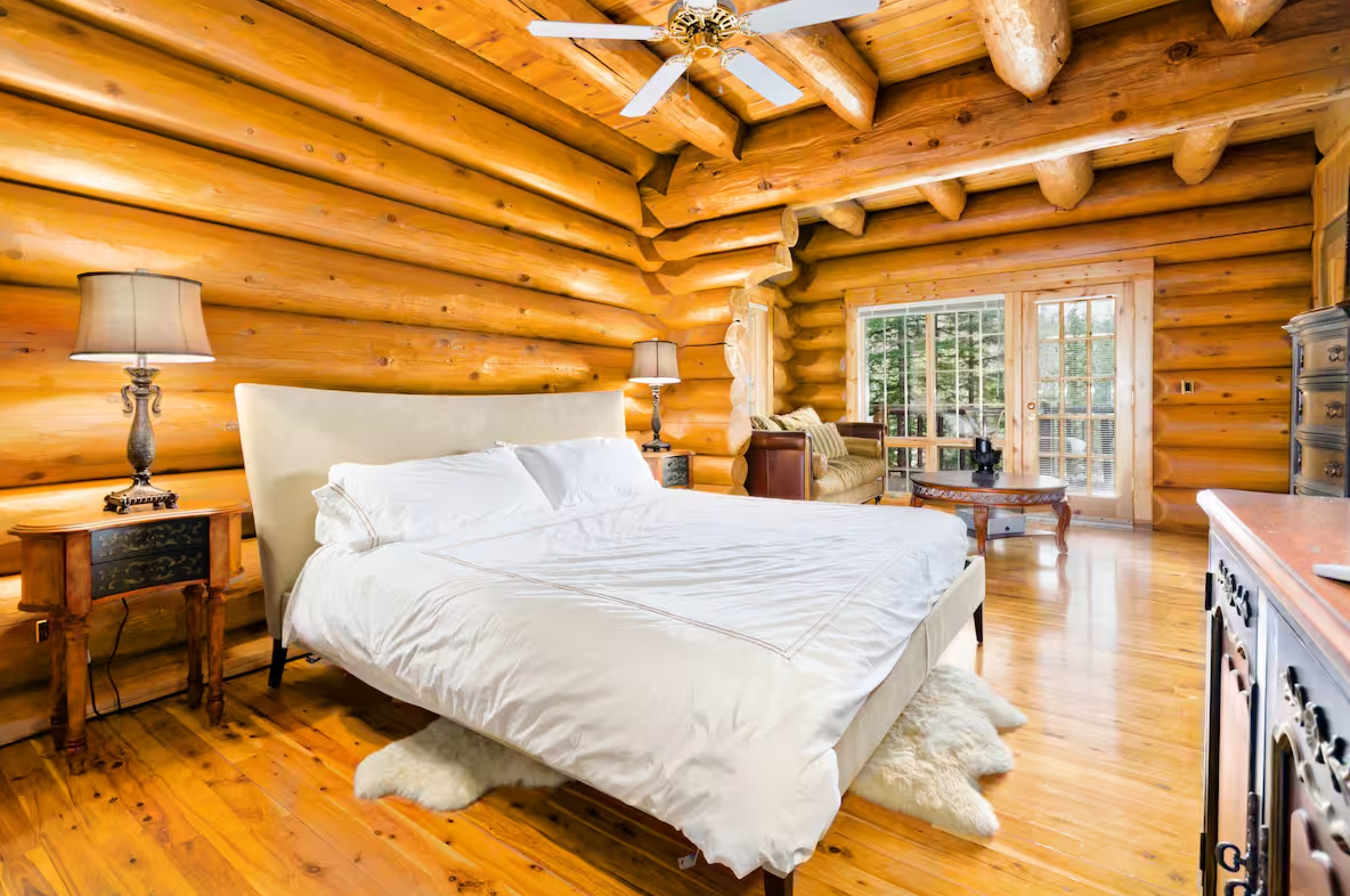 Spacious log cabin bedroom with white bedding and wooden beam ceiling.