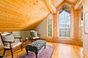Cozy sitting area in log cabin with pine floors and large windows.