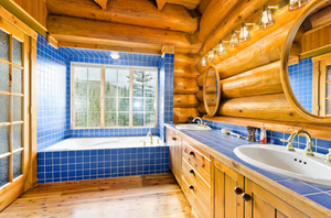 Luxurious log cabin bathroom with blue tile and double vanity.
