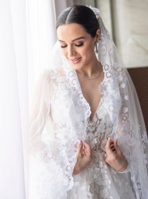 Hermosa novia modela su vestido el día de su matrimonio. Es un vestido moderno con un velo español clásico.