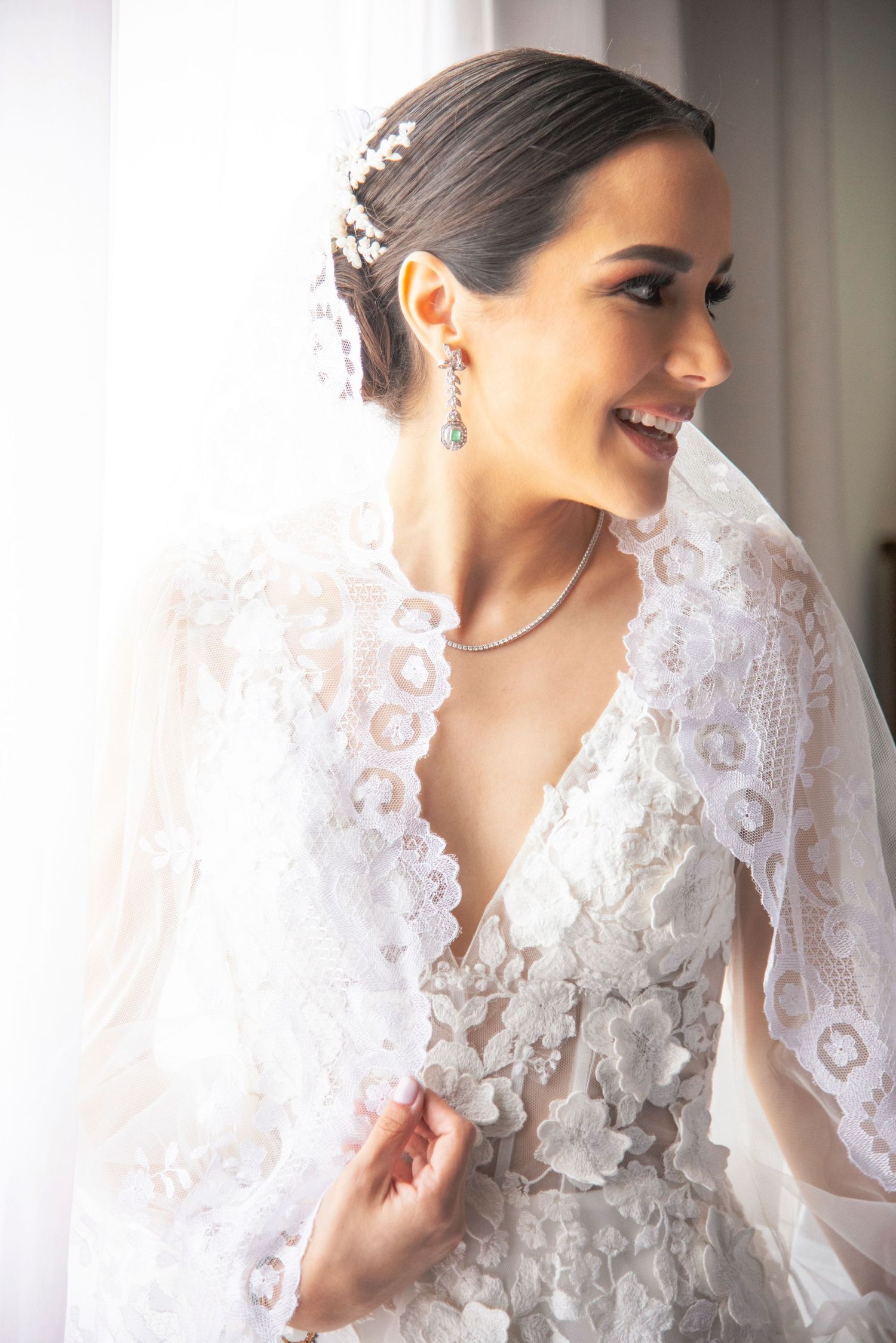 Hermosa novia observa de perfil a algo que la hace sonreir. Su aspecto es bello y clásico.