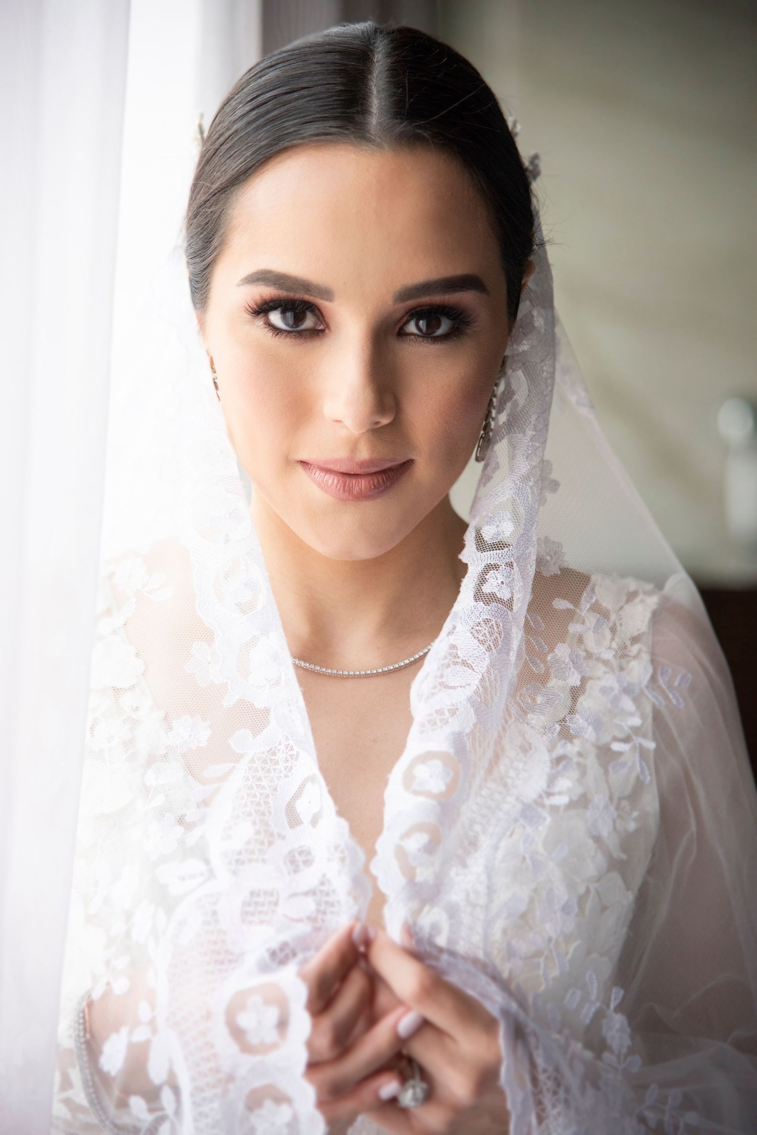 Hermosa novia con velo español observa de frente a la cámara con una mirada tierna.