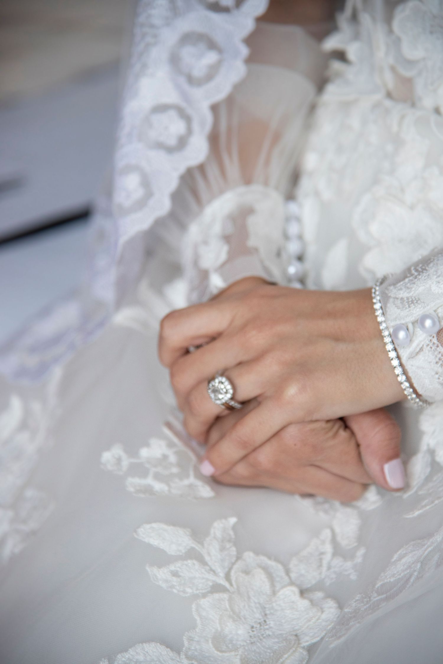 Foto de las manos de una novia el día de su boda con los anillos de matrimonio y de compromiso. Foco selectivo