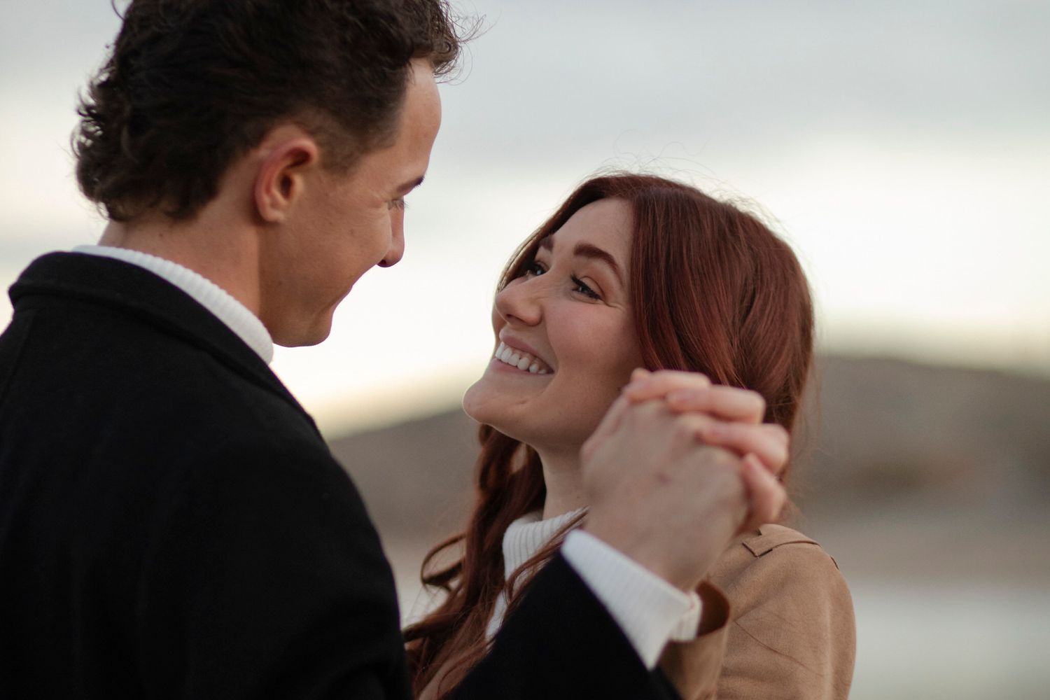 Over his shoulder, she smiles and holds his hand.