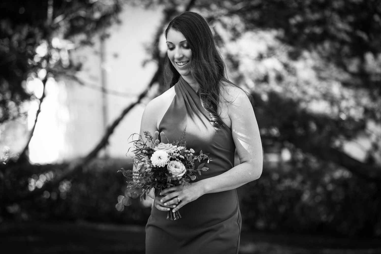 A person in formal attire holds a beautiful floral bouquet in a black and white photo.