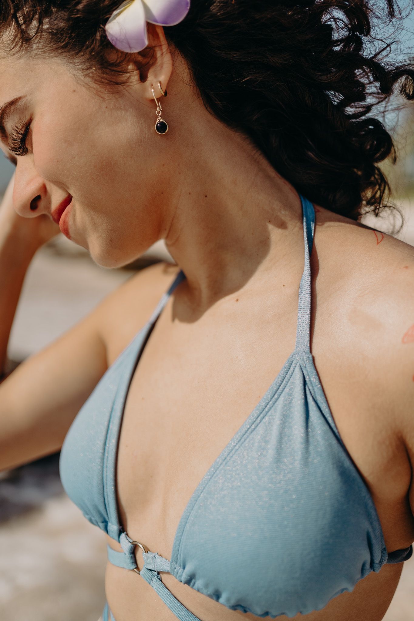 Close-up detail shot of blue bikini top and earring in warm sunlight photoshoot in Puerto Morelos.