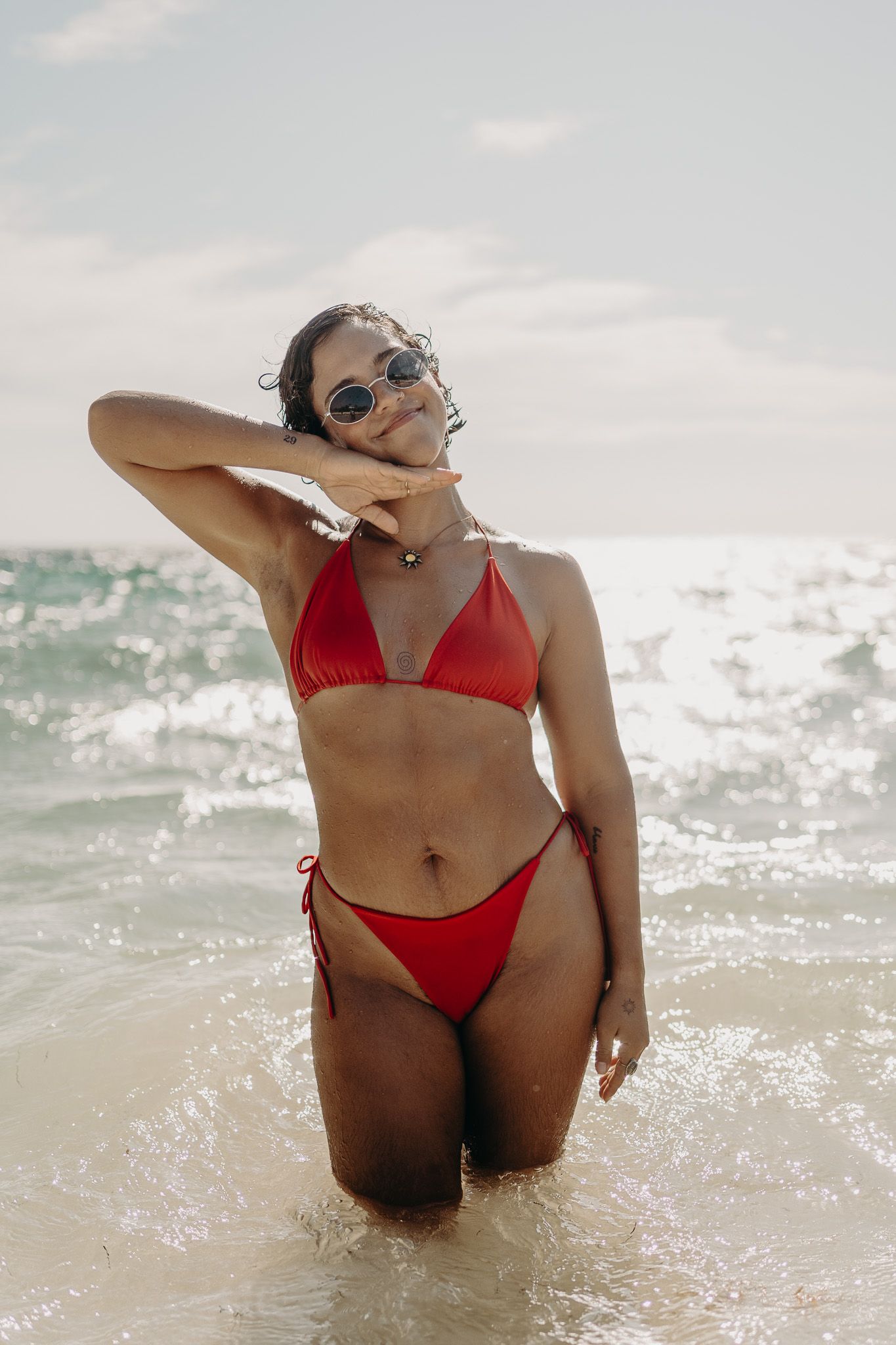 Woman in red bikini poses confidently in crystal clear ocean waters photoshoot in Puerto Morelos.