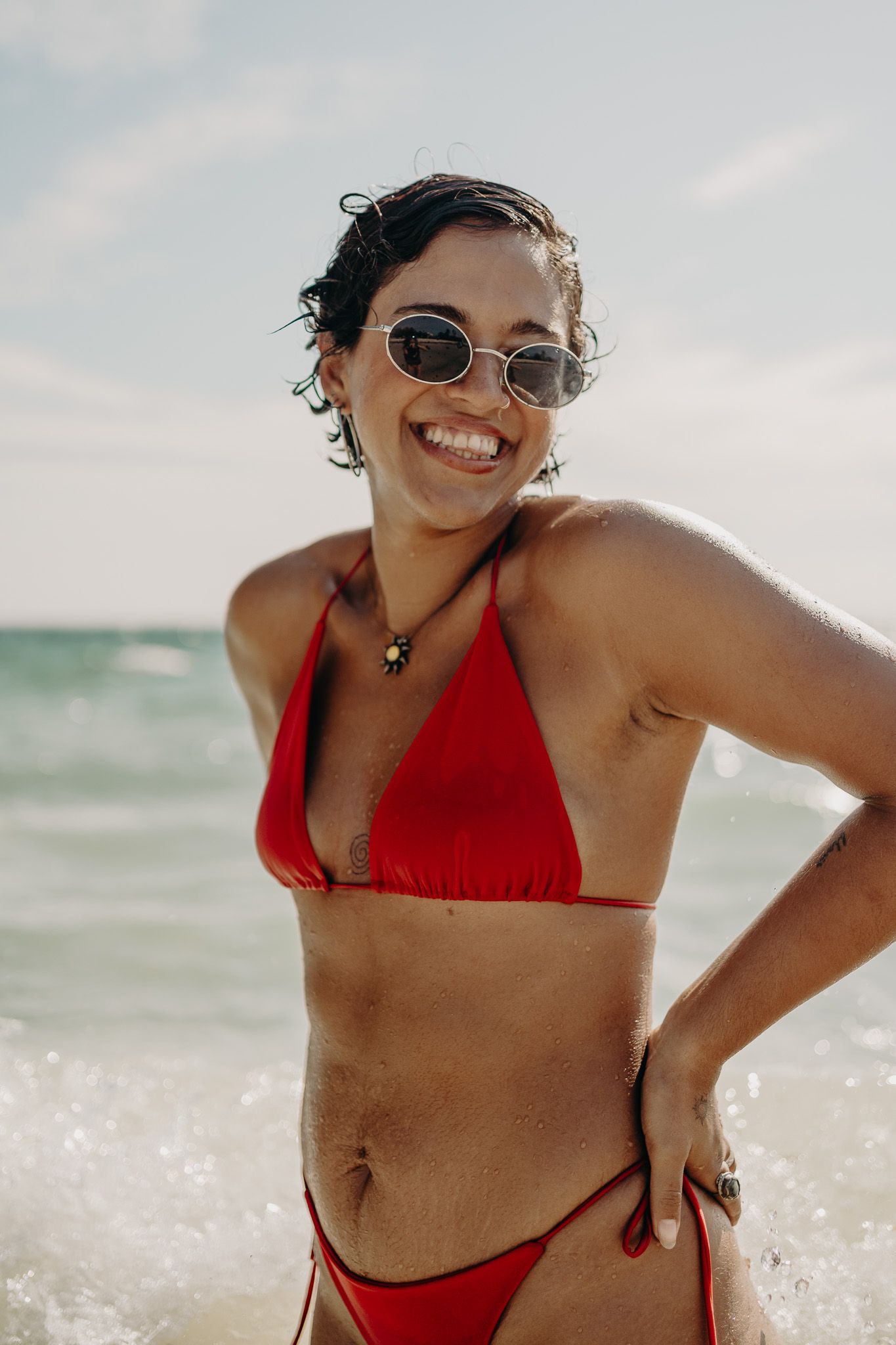 Person in red swimwear and sunglasses enjoying a sunny beach day photoshoot in Puerto Morelos.