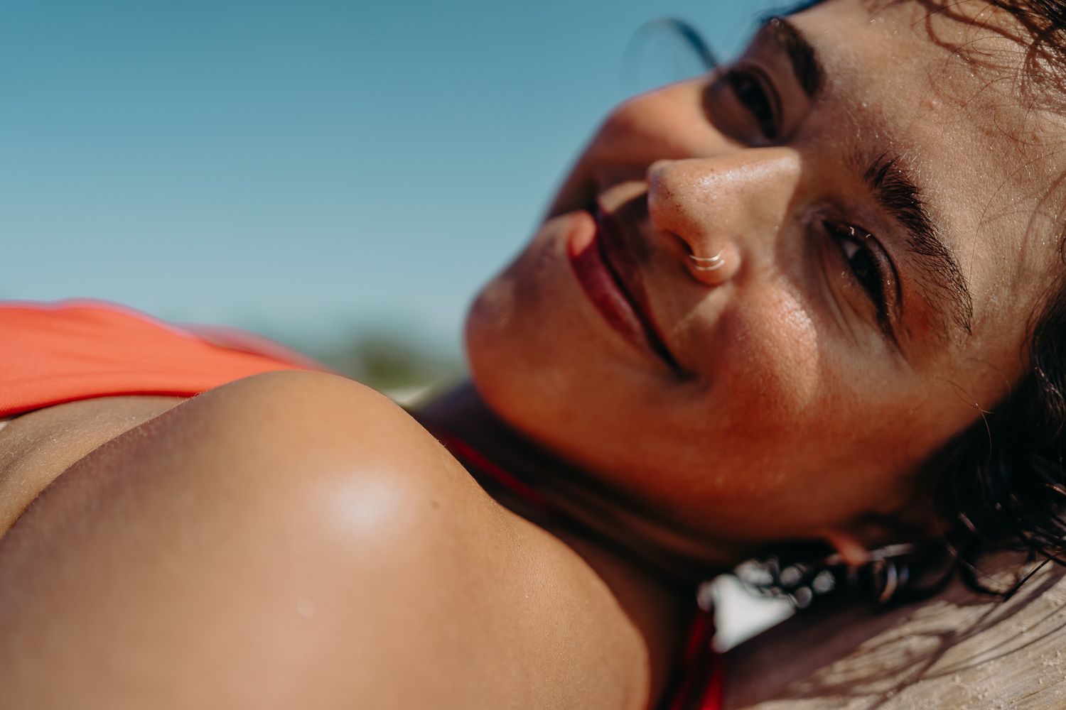Sunlit close-up portrait in coral swimwear against bright blue sky photoshoot in Puerto Morelos.