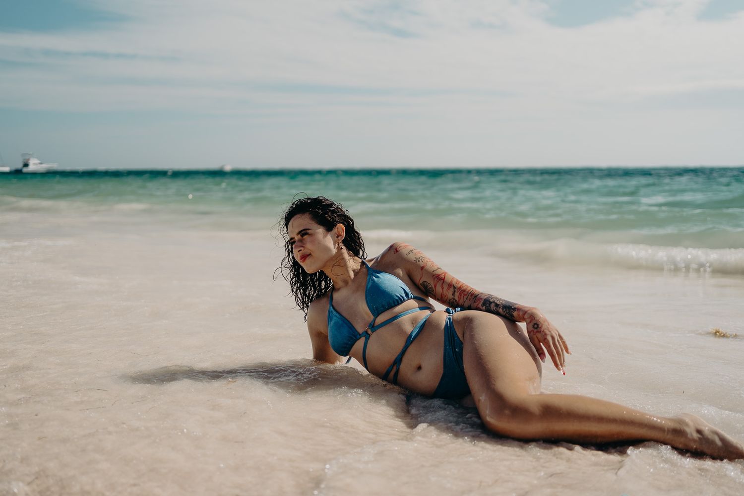 Playful beach pose in turquoise swimwear with ocean horizon view photoshoot in Puerto Morelos.