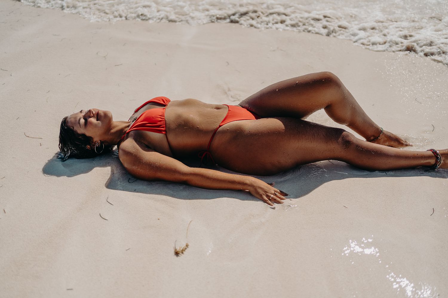 Sunbathing on sandy beach in coral red bikini photoshoot in Puerto Morelos.