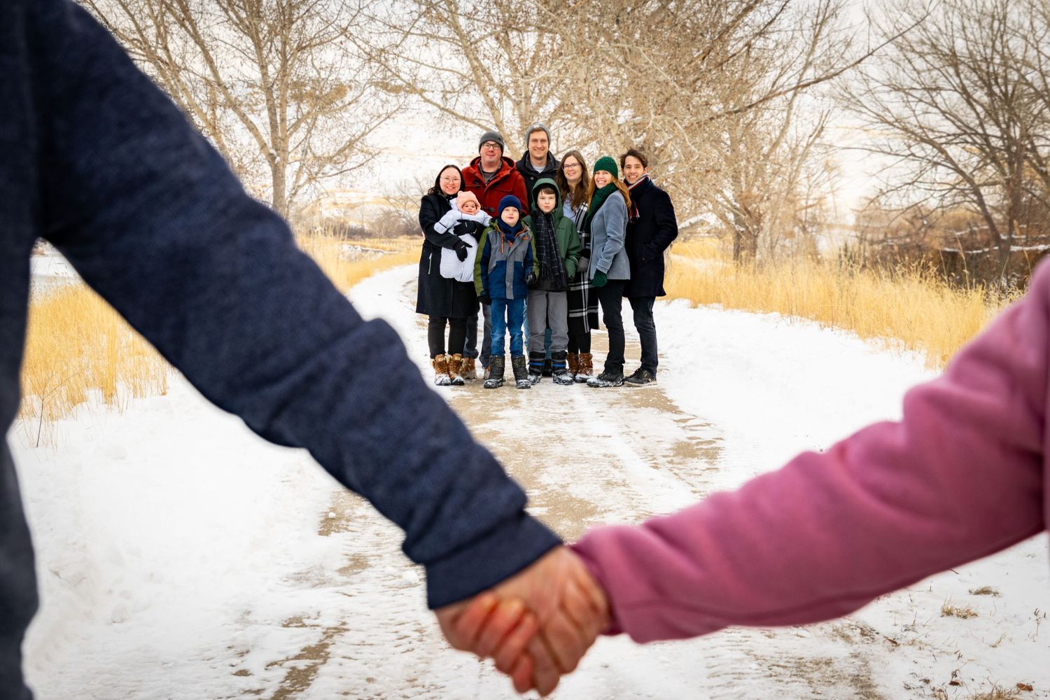 a couple holding hands with their family smiling together behind them.