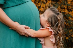 daughter kissing moms pregnant belly