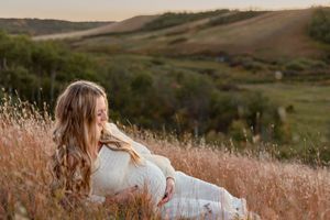 valley views of pregnant mama sitting on hill