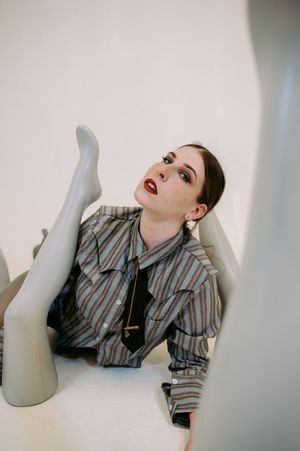 Fashion model in striped shirt poses dramatically against white backdrop in artistic triptych photo series.