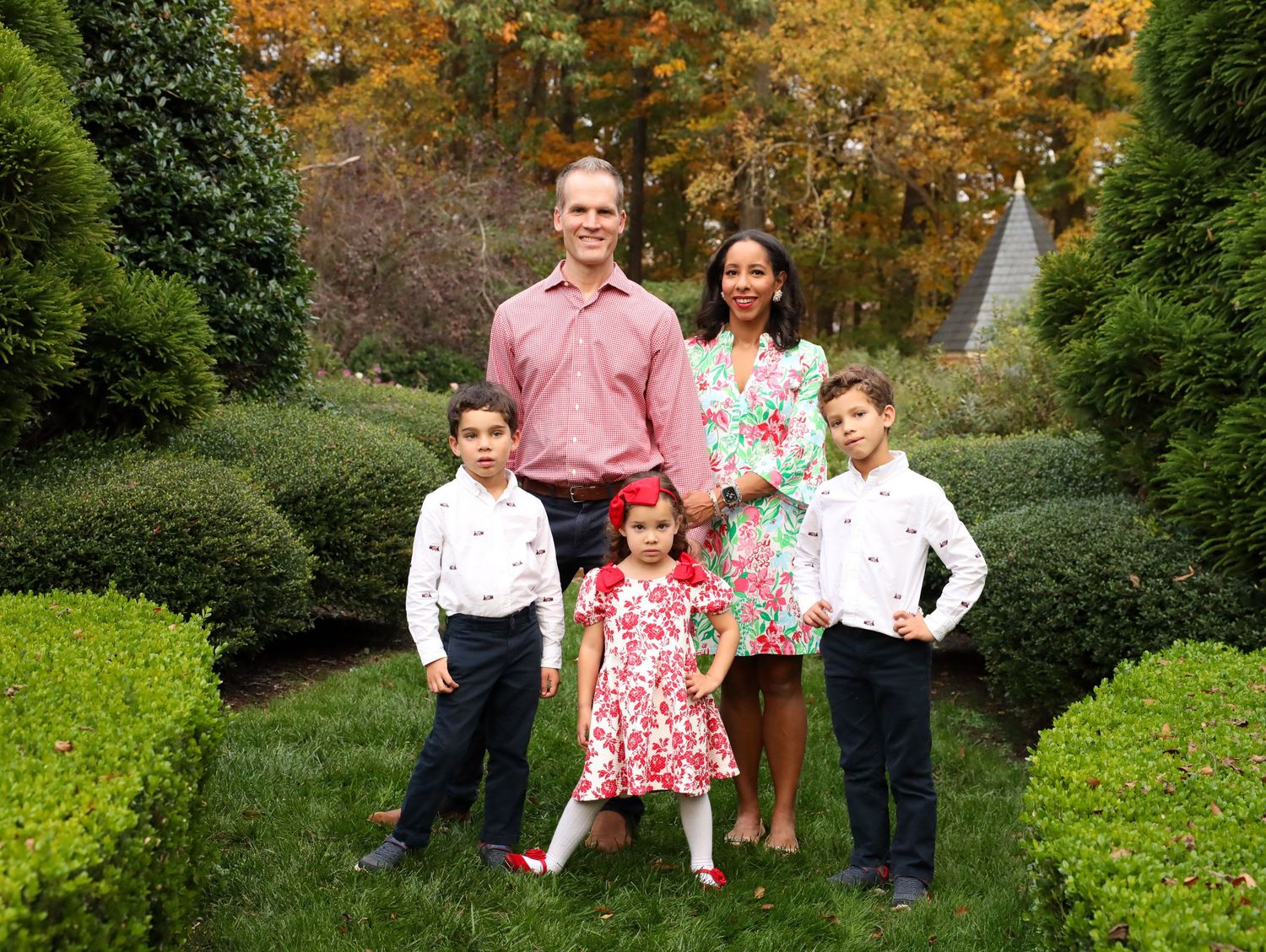 A family poses together in a modern home interior with wooden floors and black stair railings.