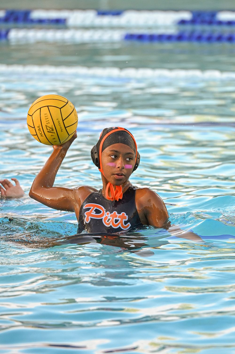 Water polo player practices ball handling drills during training session in pool.