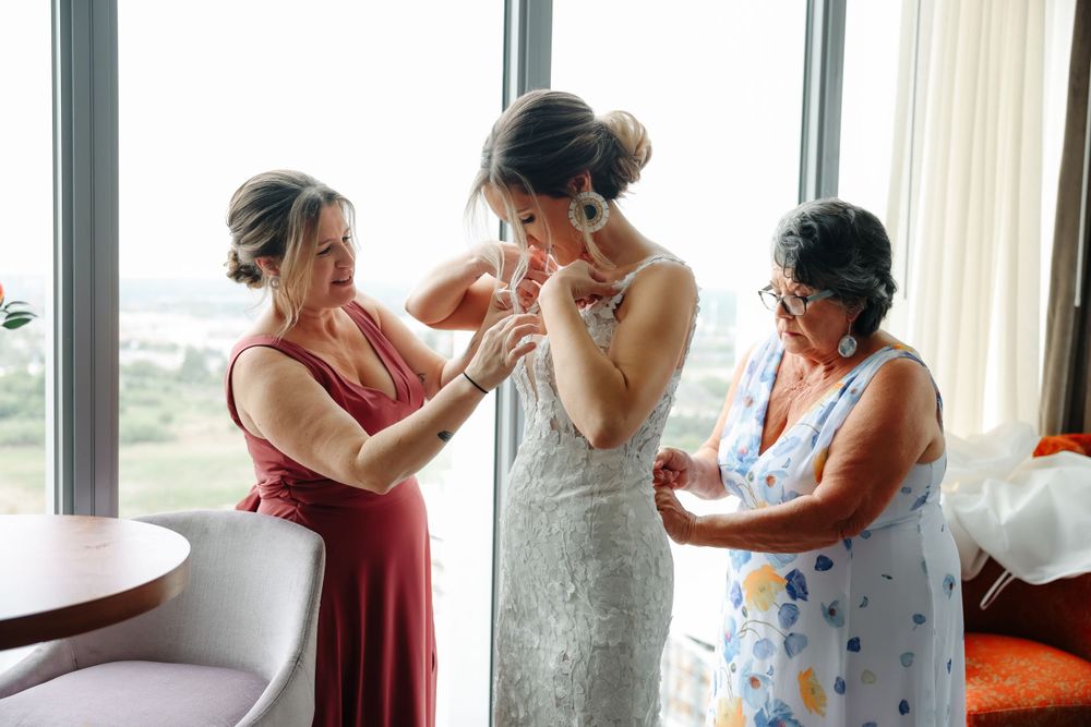 Wedding preparation scene showing final adjustments being made to a beautiful lace gown.