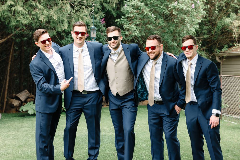 Wedding party in coordinated navy suits and sunglasses posing outdoors.
