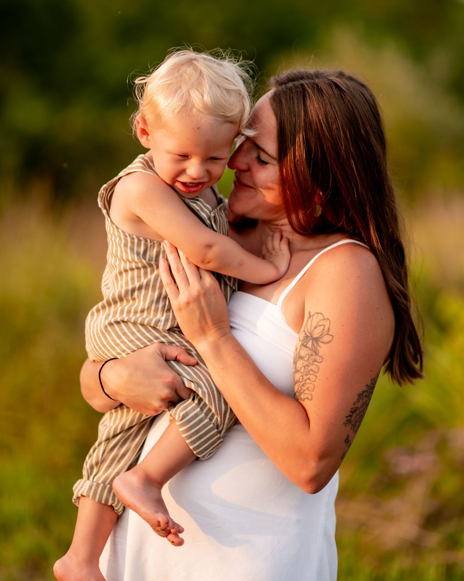 A tender moment between parent and child sharing laughter and cuddles in a sunlit field during golden hour.