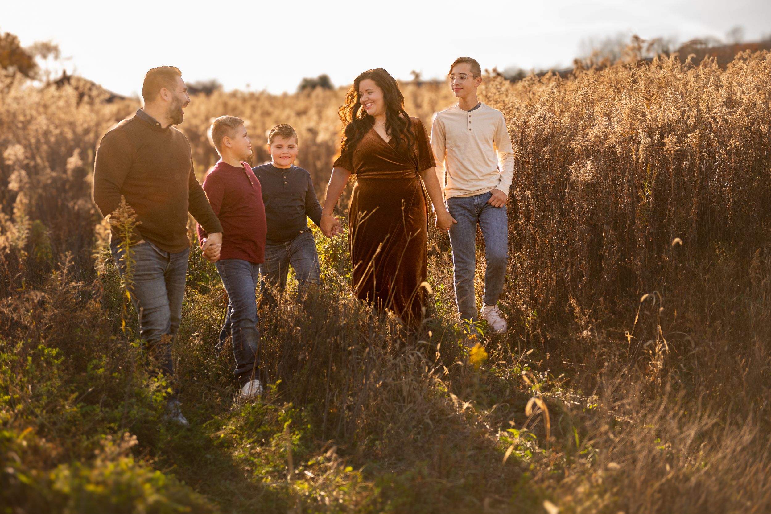 Group walking together through a golden field at sunset with warm backlit lighting creating a dreamy atmosphere.