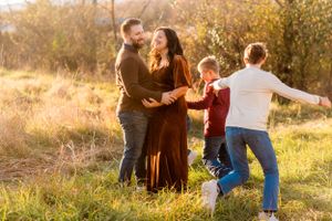 A warm, loving moment between a family playing together in a golden autumn field at sunset.