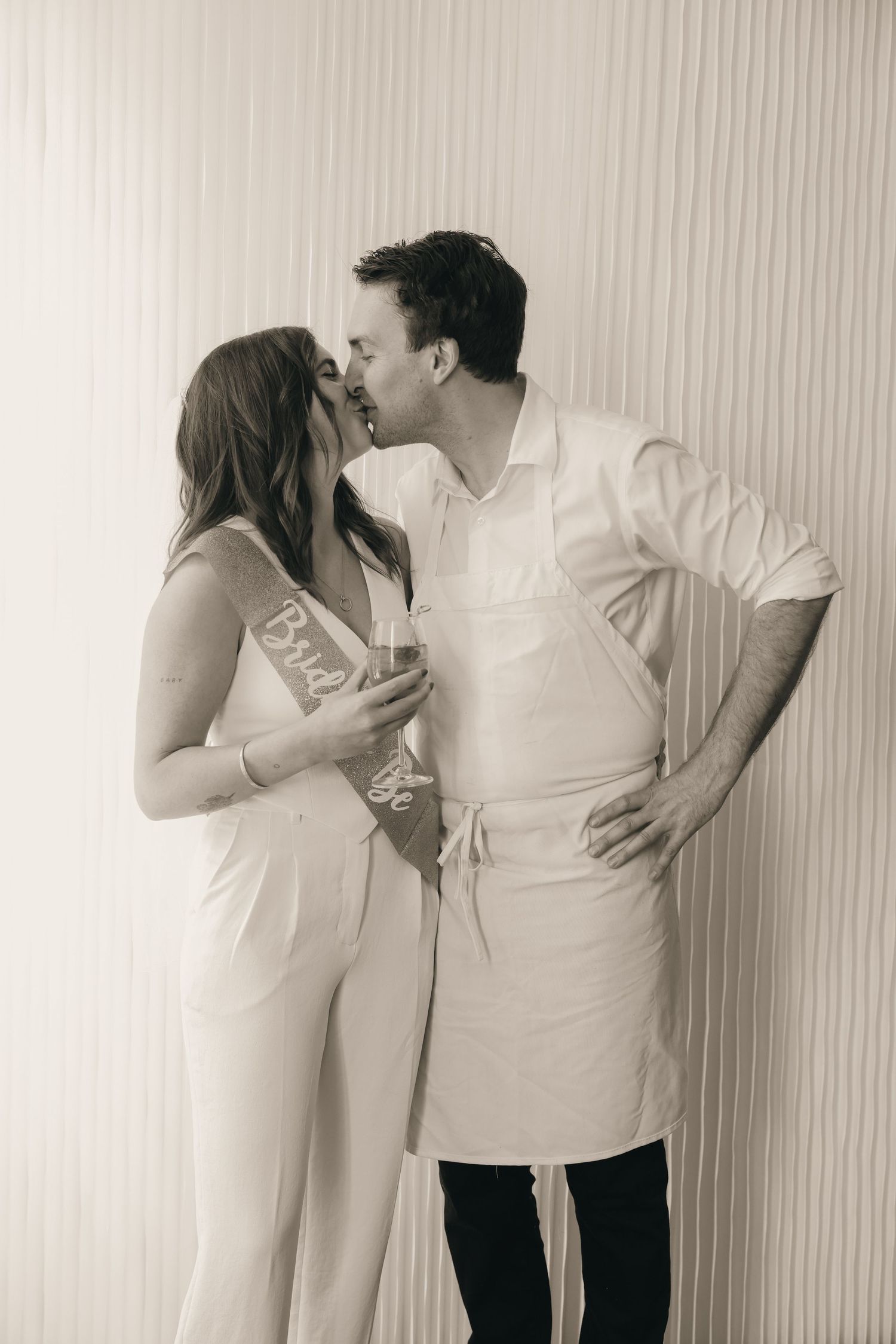 A sepia-toned intimate moment captured against a minimalist background.