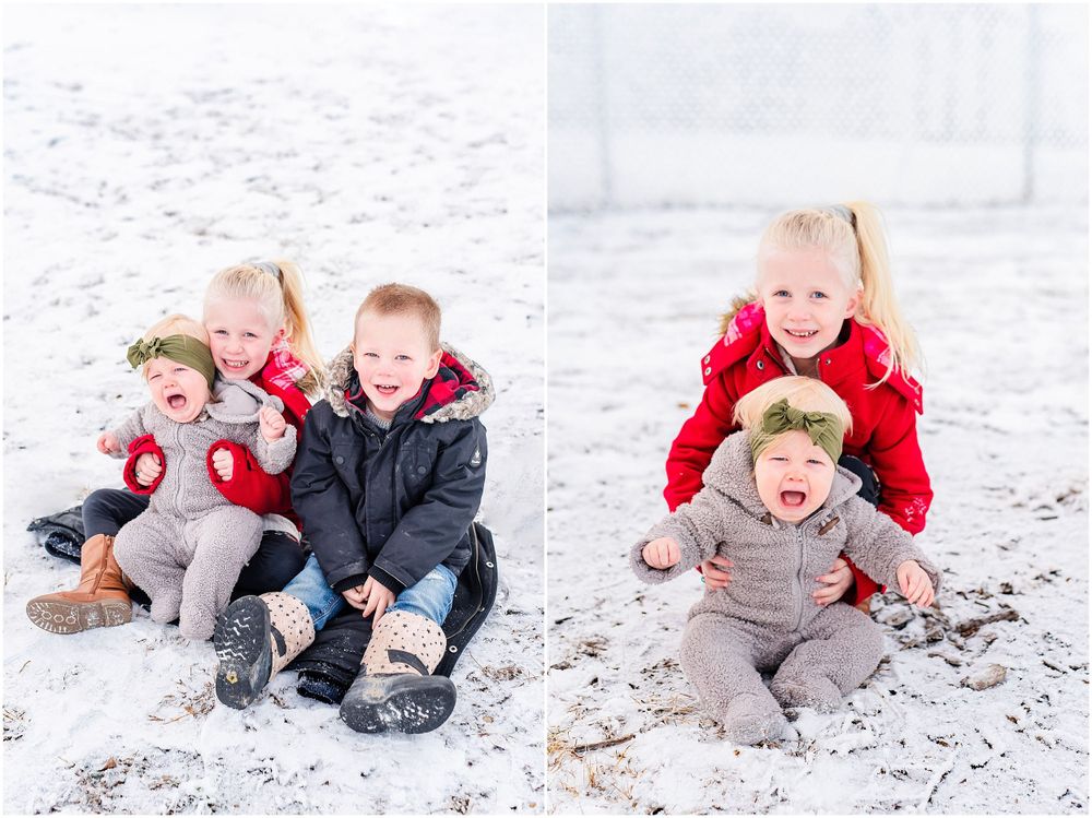 Two children playing and laughing together in the snow wearing winter coats and boots.