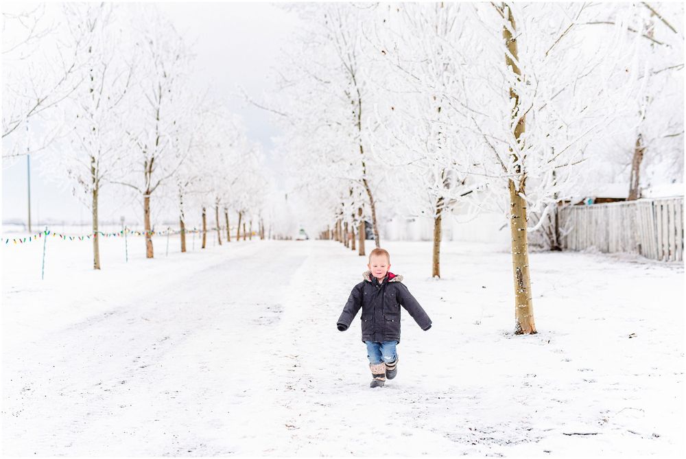 Person running down a snow-covered path lined with bare winter trees.
