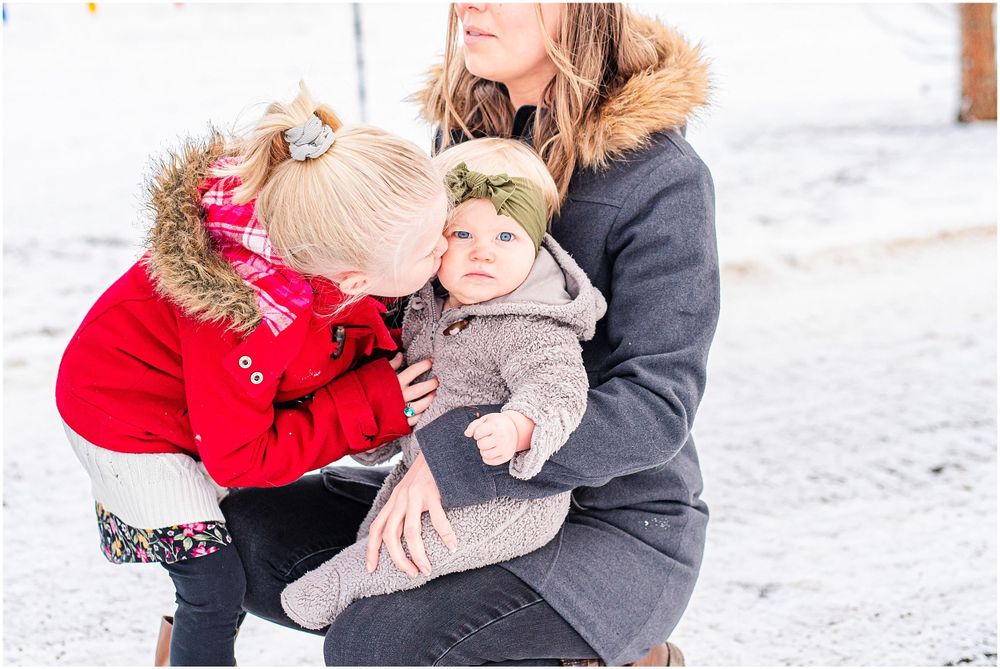 Mother holding children close in a snowy winter setting.
