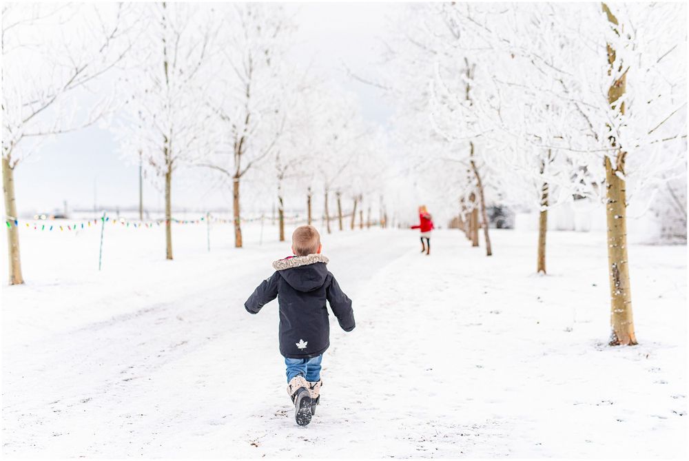 Child running through a snow-covered path lined with white winter trees.
