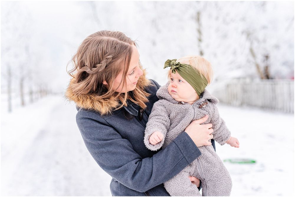 Mother and baby share a tender moment against a snowy winter landscape.