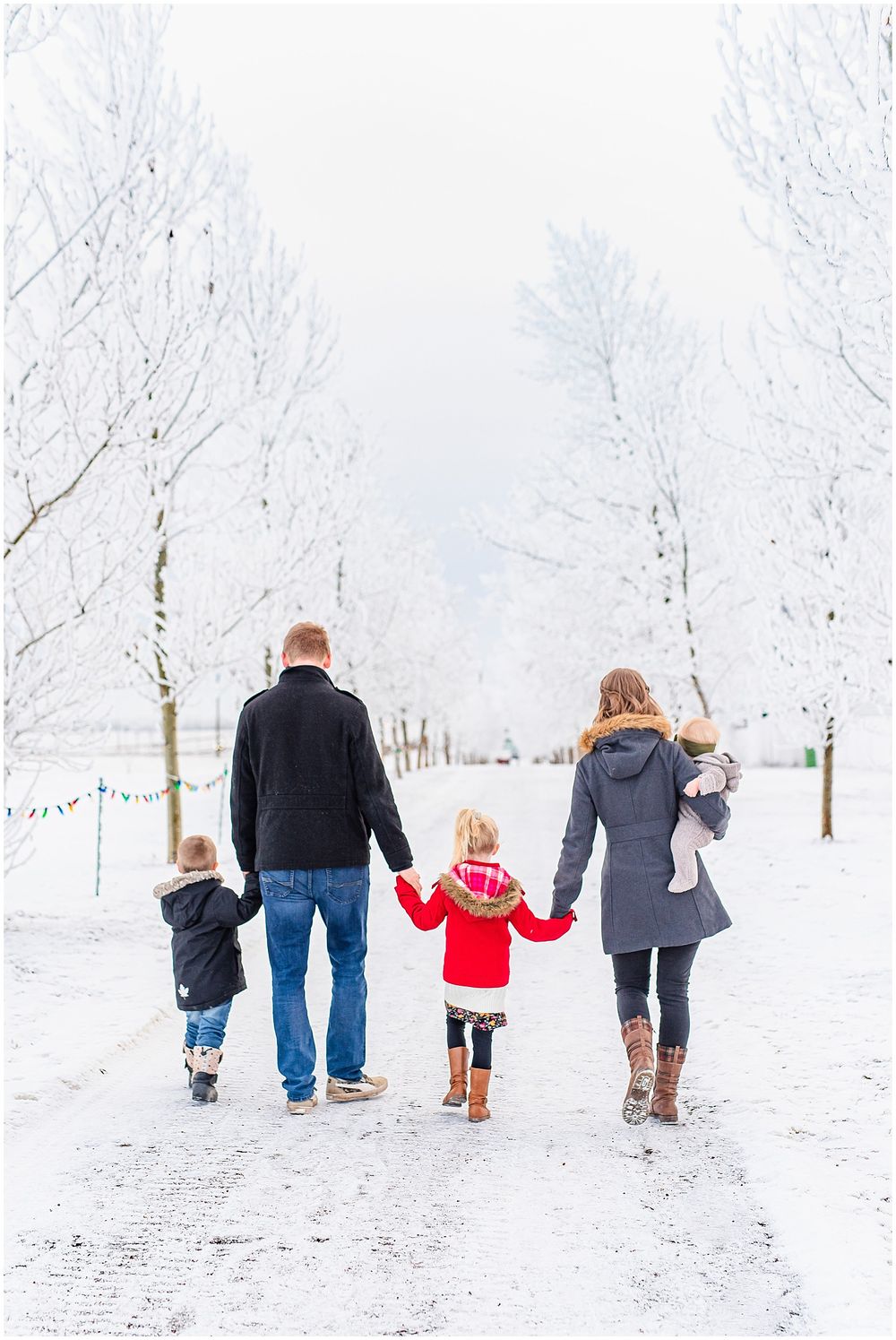 Family walking together on a snow-covered path among bare winter trees.