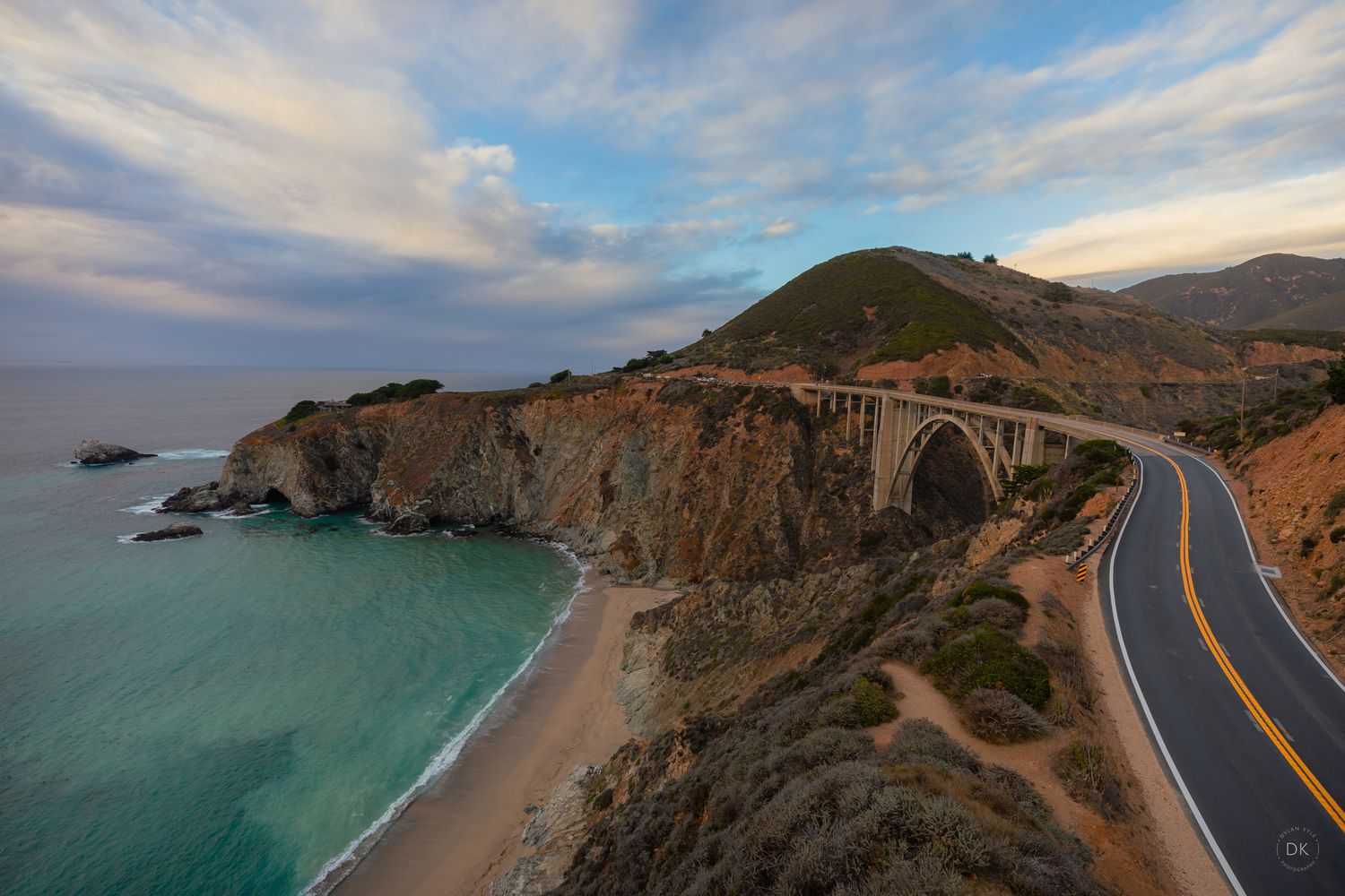 Scenic aerial view of Bixby Creek Bridge along California's Pacific Coast Highway with turquoise waters and rugged cliffs.