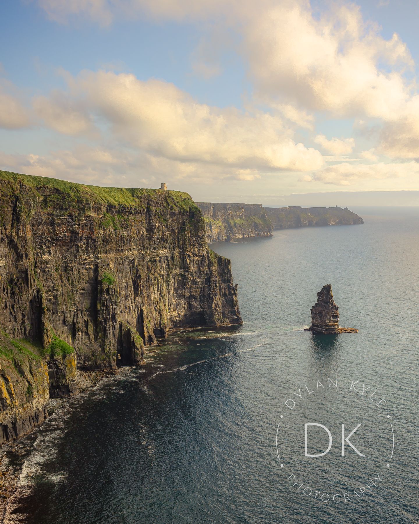 Dramatic sunset view of the Cliffs of Moher with iconic sea stack formation rising from Atlantic Ocean waters in Ireland.